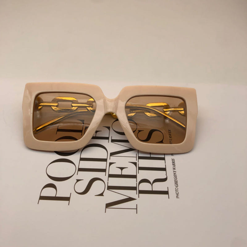 Square beige sunglasses with gold chain detail and amber-tinted lenses