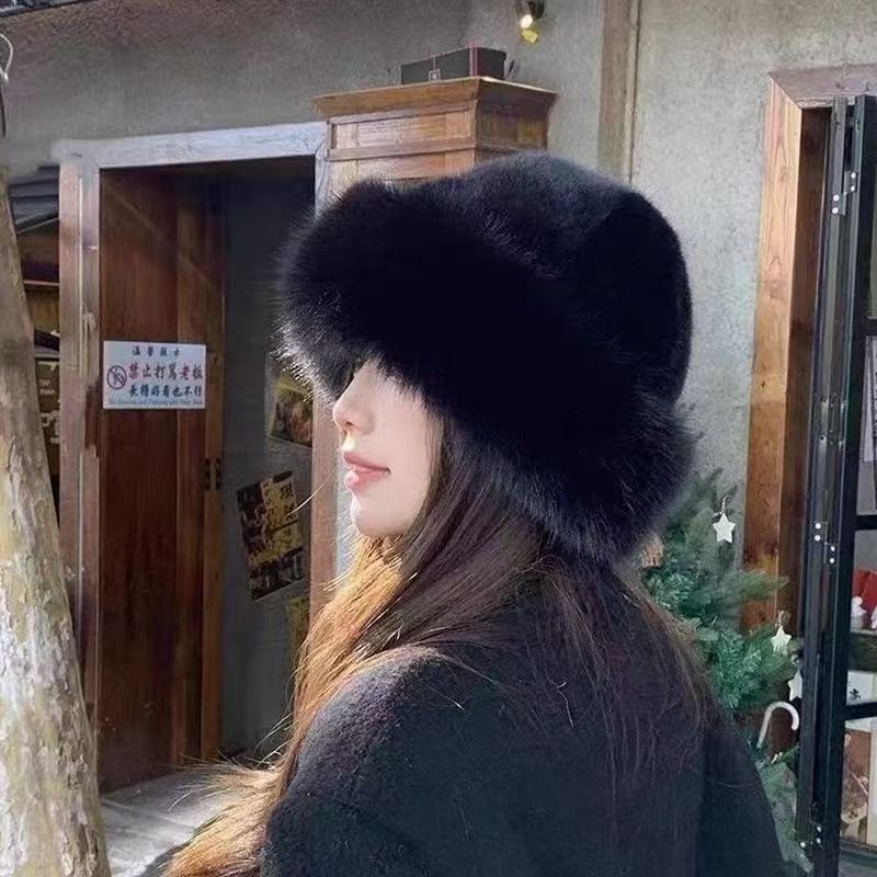 Person wearing a black fur hat indoors with wooden furniture and a Christmas tree in the background.
