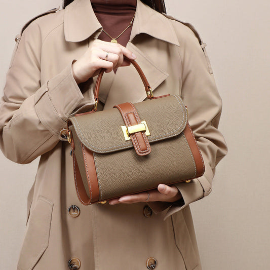 Person holding a brown handbag with a beige background