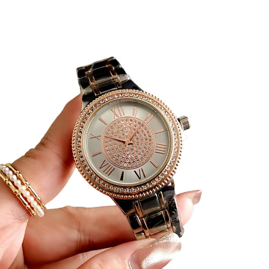 Rose gold watch with diamond accents held by a hand on a white background