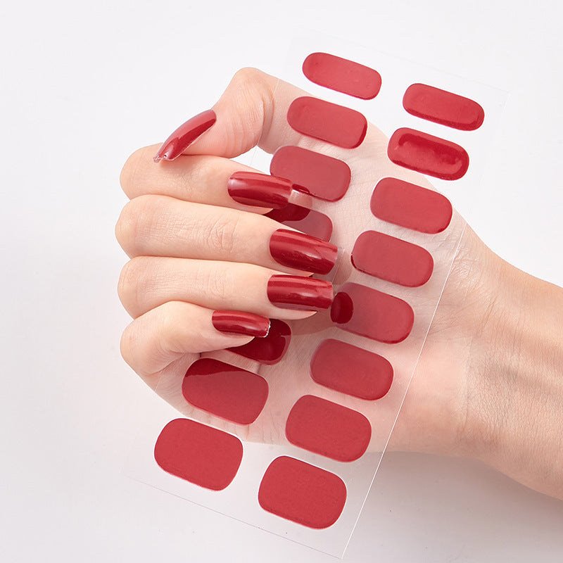 Hand with red nail polish matching a set of red nail stickers on a white background
