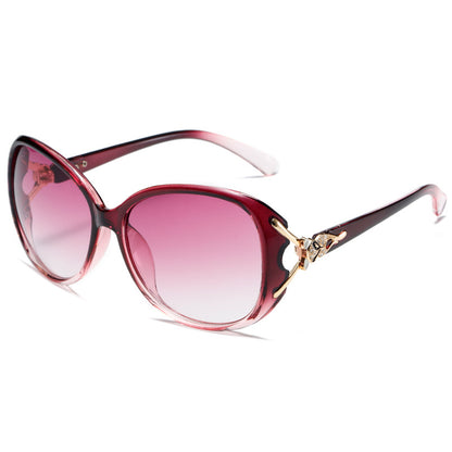 Sunglasses with pink gradient lenses and a decorative gold bow on a white background