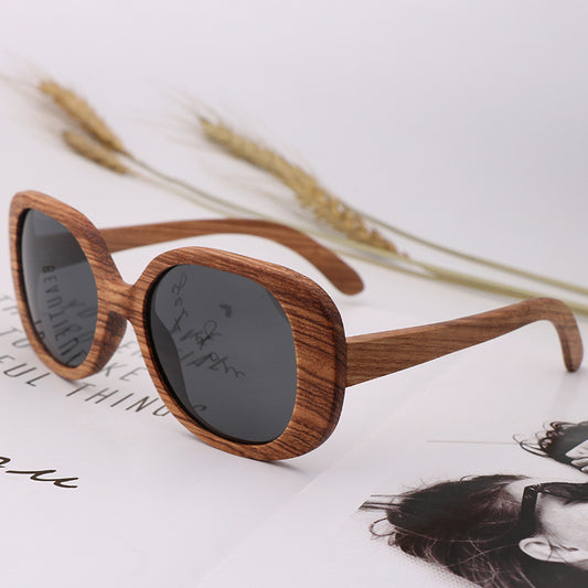 Wooden sunglasses with dark lenses on a magazine background