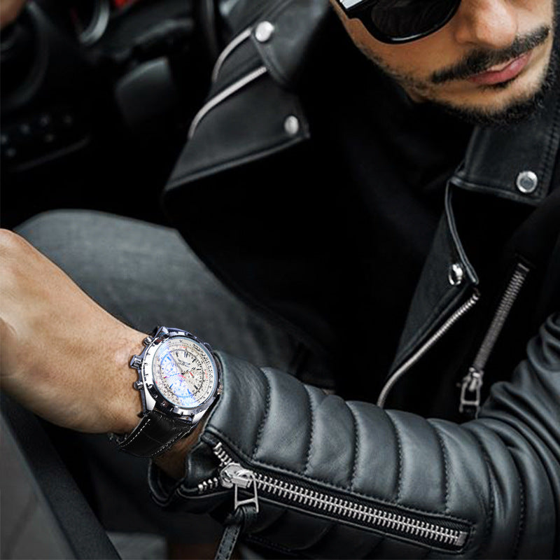 Man wearing a black leather jacket and sunglasses, sitting in a car, with a close-up of his wrist showing a watch.