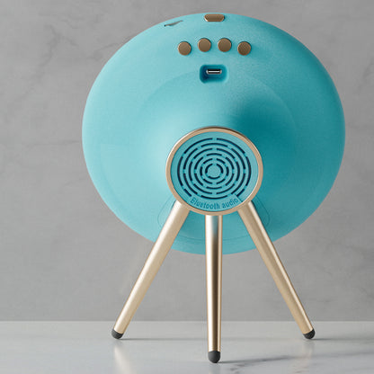 Turquoise Bluetooth speaker with gold legs on a gray background