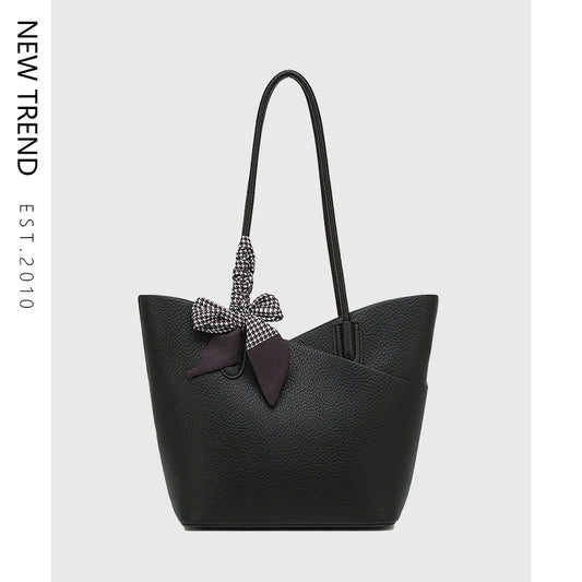 Black handbag with a decorative bow on a light gray background