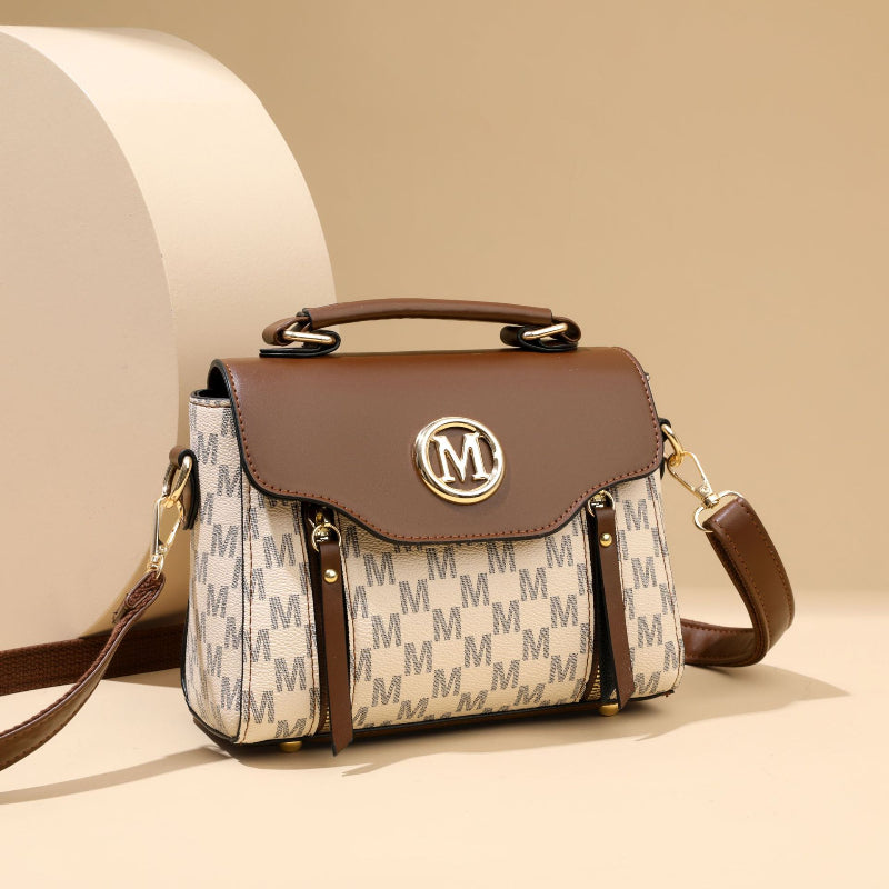Brown monogram crossbody handbag with front flap, gold M emblem, adjustable shoulder strap