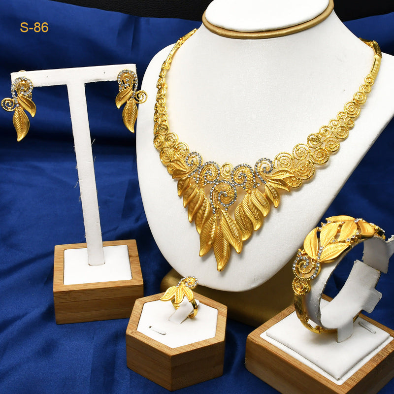 Gold necklace, earrings, and ring set on a blue fabric background