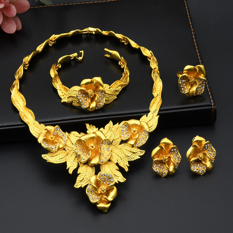Gold-plated floral jewelry set with necklace, matching bracelet, and stud earrings