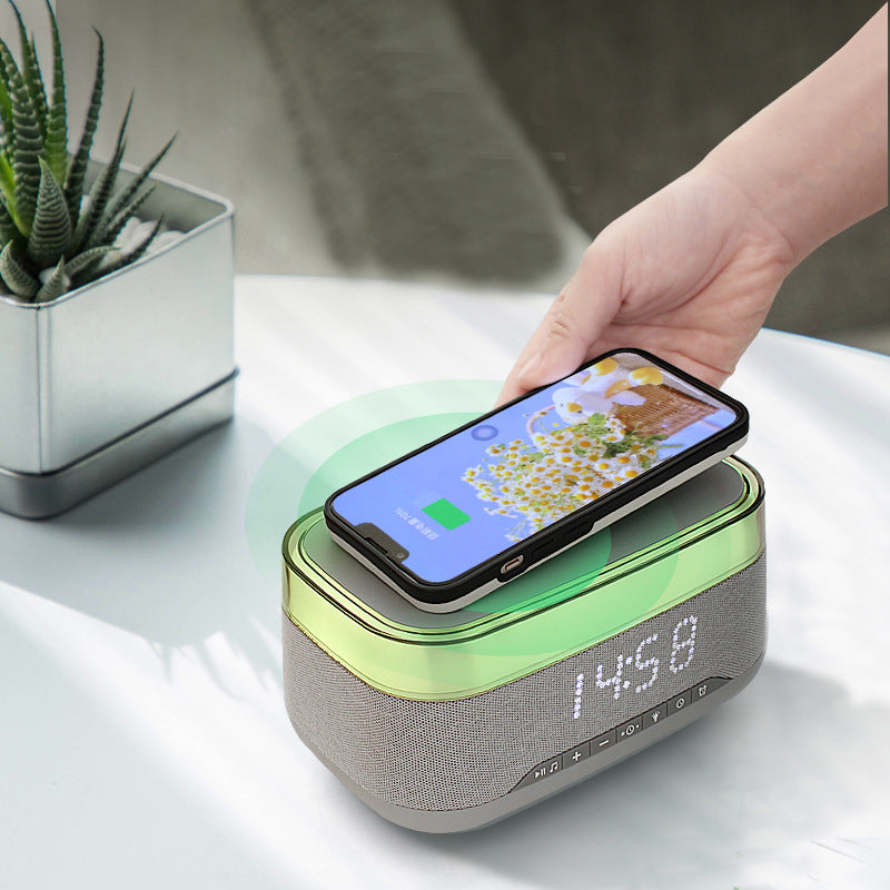 White and gray speaker acting as wireless charger with phone placed on top