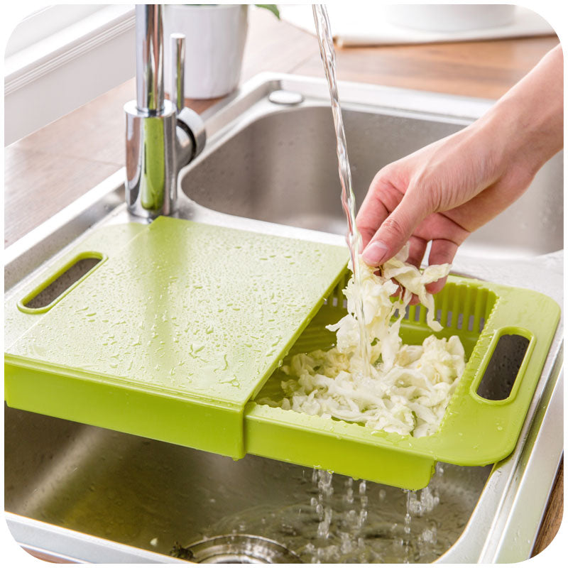 Person washing chopped vegetables under running water on a green cutting board over a sink.