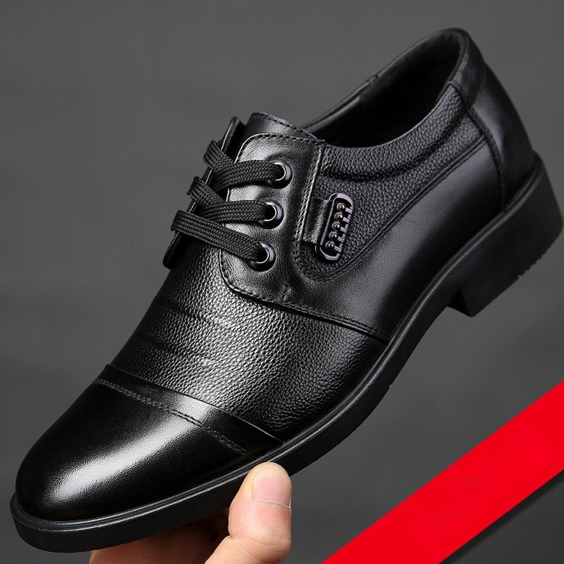 Black leather dress shoe held by a hand against a dark background