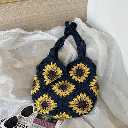 Navy blue handbag with yellow sunflower patterns on a white fabric background