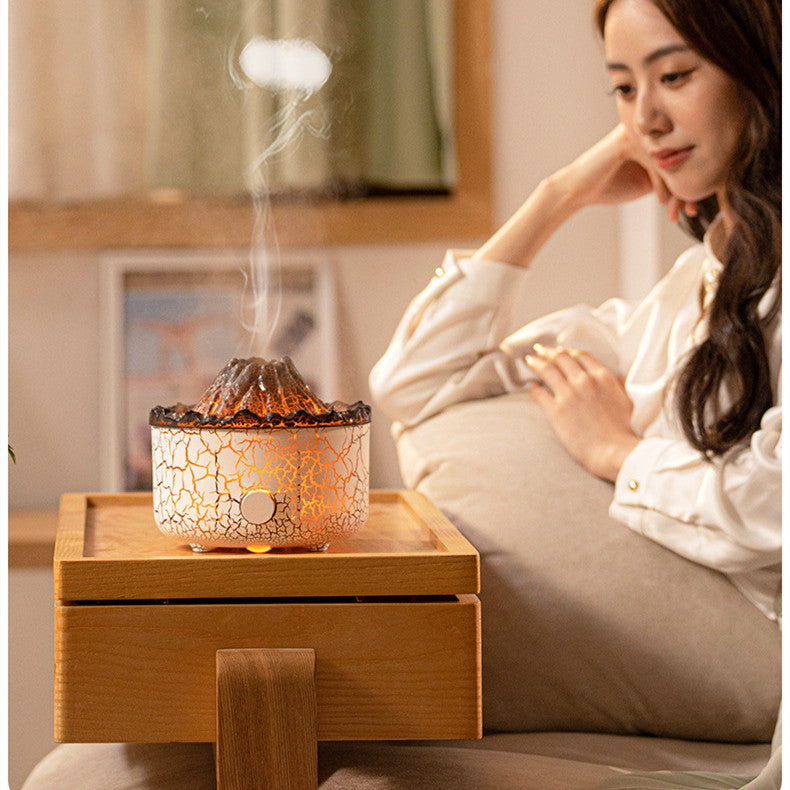 Woman sitting on a couch next to a crackled glass diffuser emitting steam.