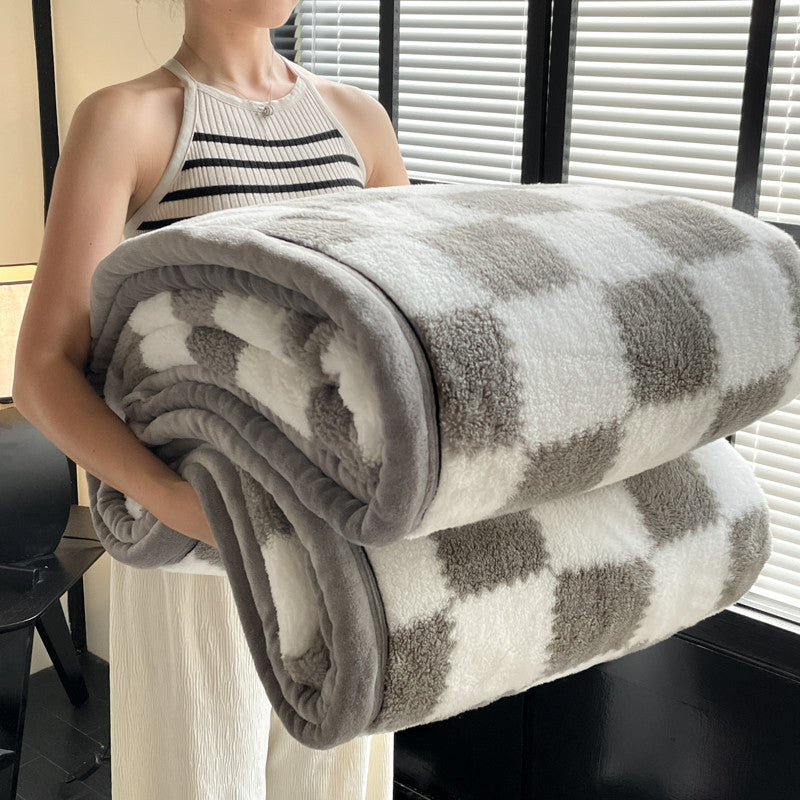 Velvet plaid blanket rolled with gray square blocks on white, plush pile, HOME label