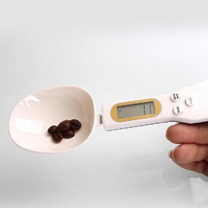 Digital kitchen scale with a scoop holding coffee beans on a white background