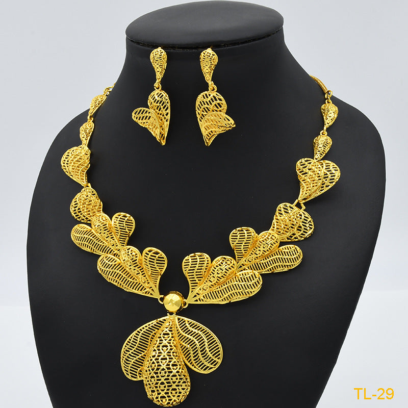 Gold necklace and earrings set on a black mannequin with a light gray background