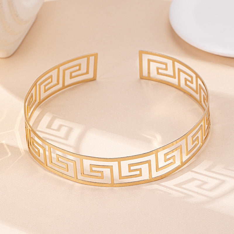 Gold-tone geometric Greek key bangle bracelet with open top detail