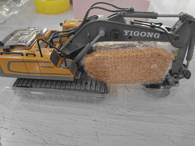 Yellow RC excavator toy with wrapped boom and bucket details, in clear packaging
