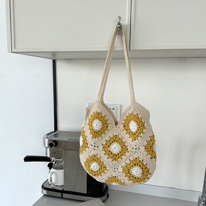 Crocheted bag with floral pattern hanging on a kitchen cabinet.