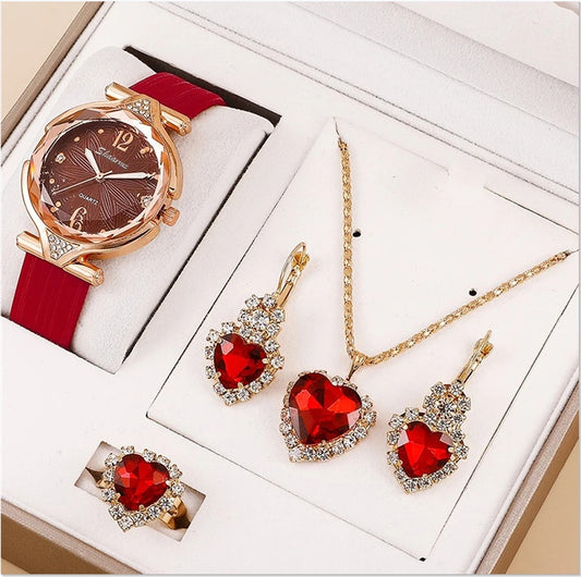 Jewelry set with heart-shaped red gemstones including a watch, necklace, and earrings on a white background.