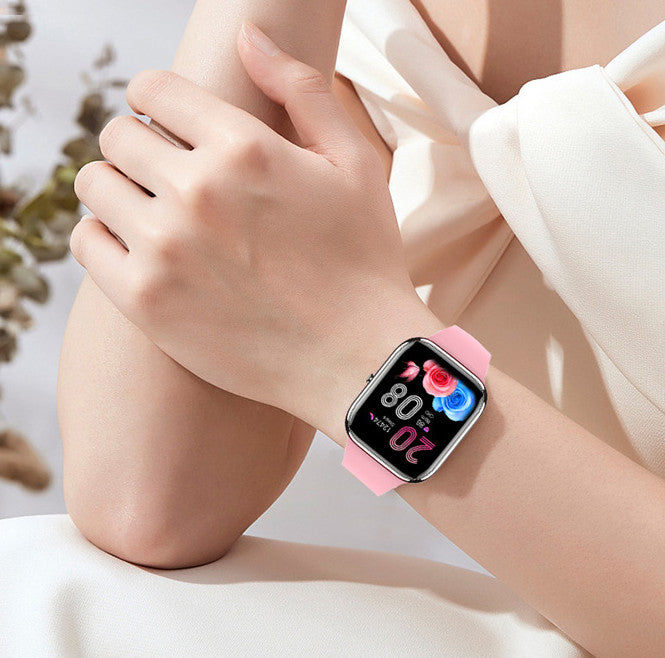 Smartwatch with a pink band on a person's wrist, with a blurred background