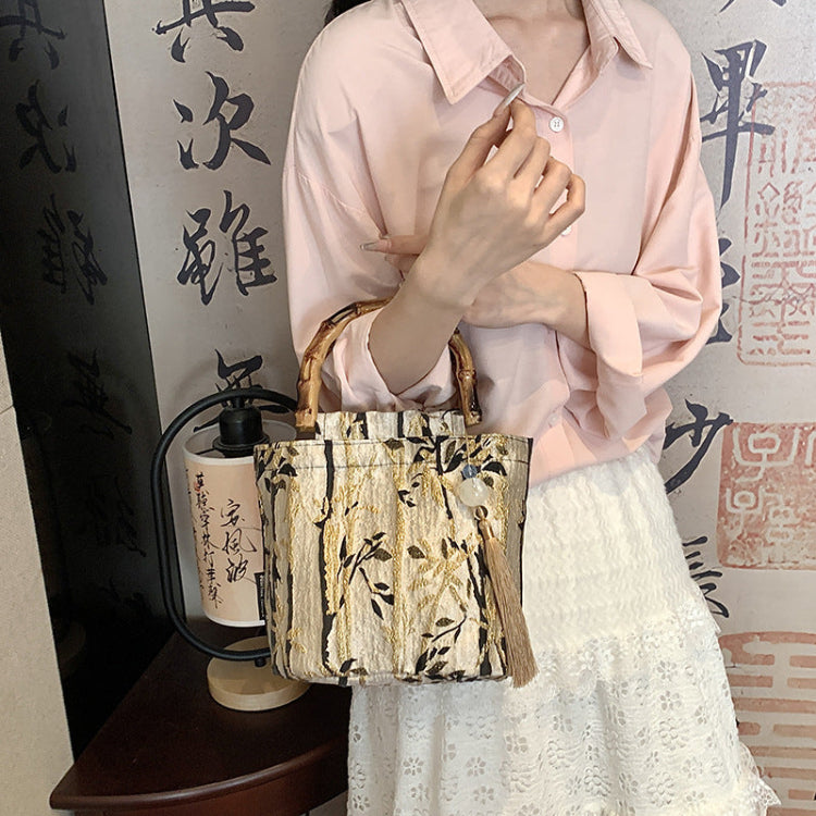 Person holding a patterned handbag in front of a decorative wall with calligraphy.