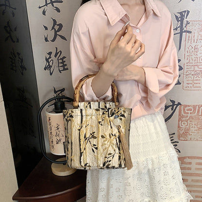 Person holding a patterned handbag in front of a decorative wall with calligraphy.