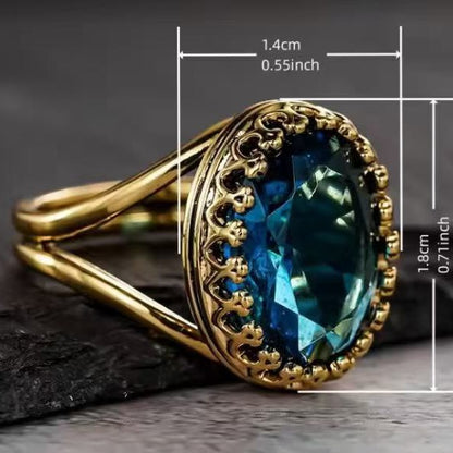 Oval teal-blue gemstone set in an antique gold ring with ornate lace-cut sidework