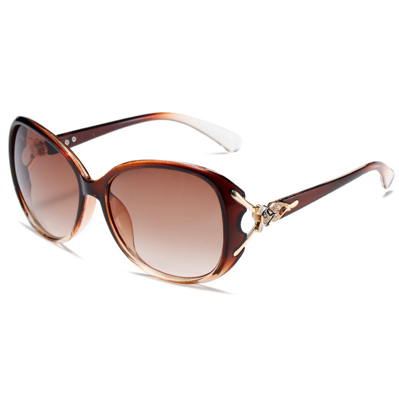 Sunglasses with brown gradient lenses and gold accents on a white background