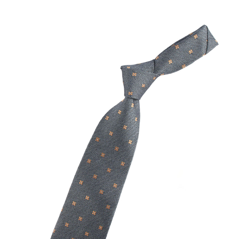 Gray tie with small patterns next to a small model of a violin on a white background