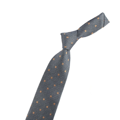 Gray tie with small patterns next to a small model of a violin on a white background