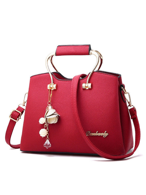 Red PU leather handbag with top handles, crossbody strap, gold hardware, hanging charm