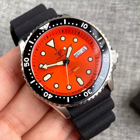 Wristwatch with a red face and black strap held in a hand against a gray background