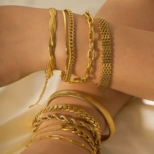 Gold-tone chain ornament bracelets stacked on wrist, with multiple mixed-link styles