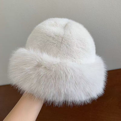 White fur hat held by a hand against a neutral background