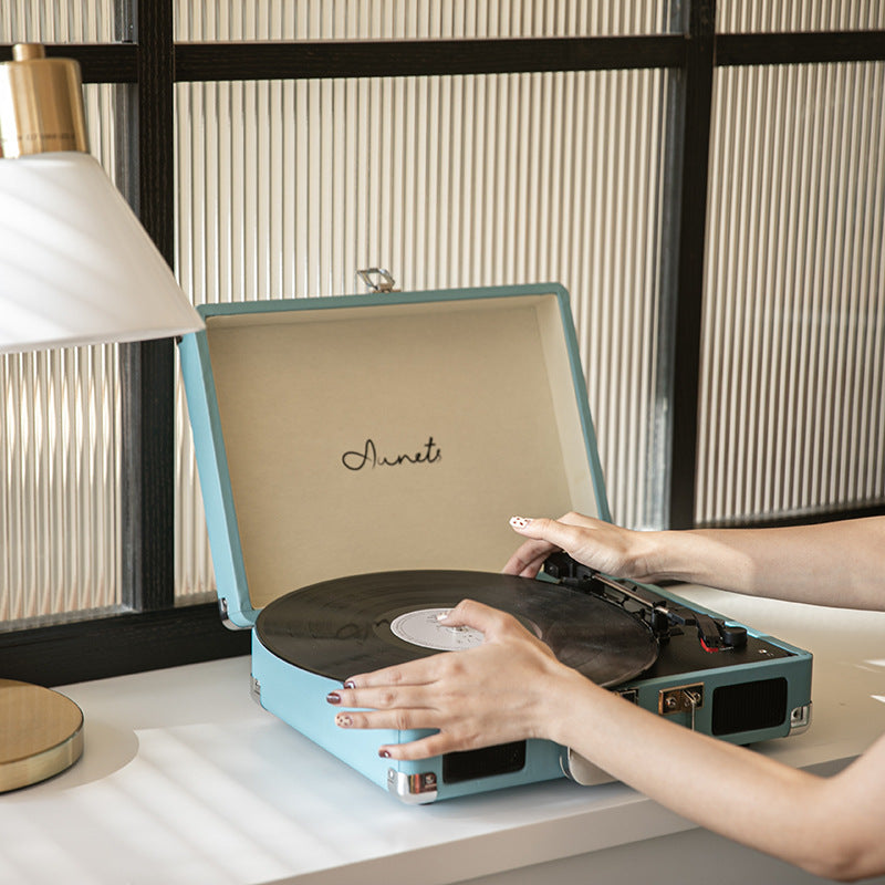 Lake blue portable Bluetooth record player phonograph with hands on spinning record
