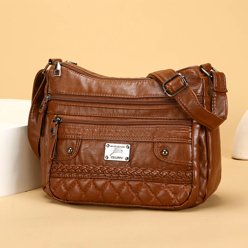 Brown leather handbag with multiple pockets and a brand label on a beige background