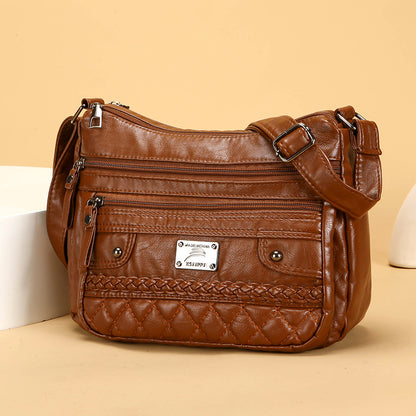 Brown leather handbag with multiple pockets and a brand label on a beige background