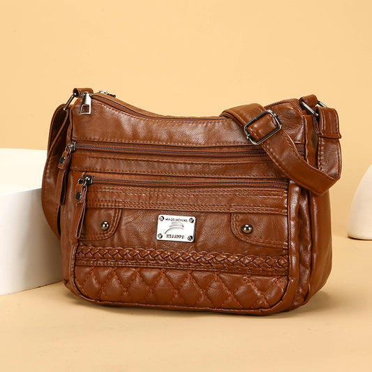 Brown leather handbag with multiple pockets and a brand label on a beige background