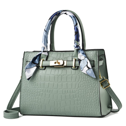 Light green croc-textured tote bag with blue patterned scarf handles