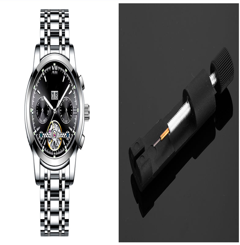 Silver wristwatch with a black face on a white background, next to a black battery pack.