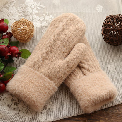 Pair of beige fuzzy gloves on a decorative surface with floral and decorative elements.