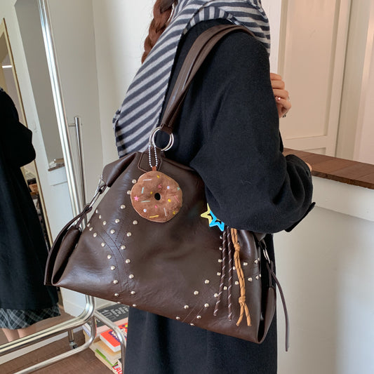 Person holding a brown polka dot handbag with decorative elements indoors.
