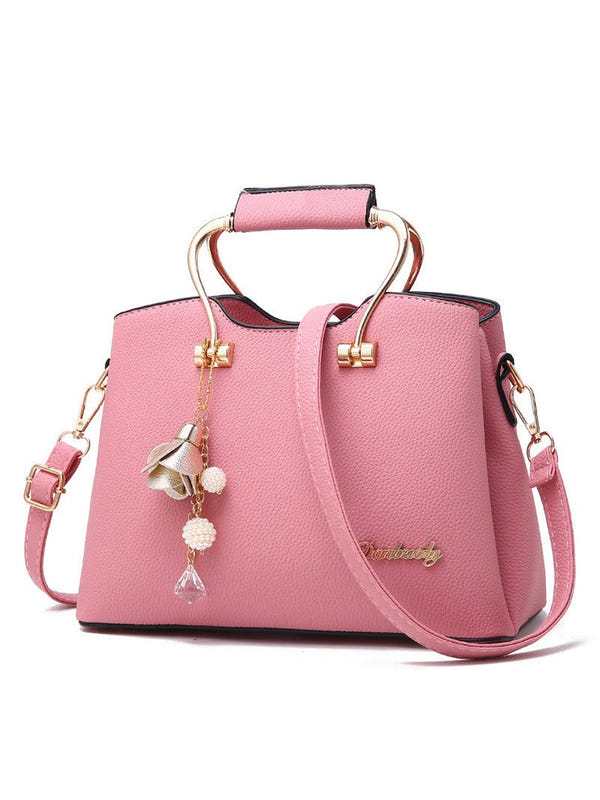 Pink textured handbag with top handle and crossbody strap, gold-tone lock details and charm