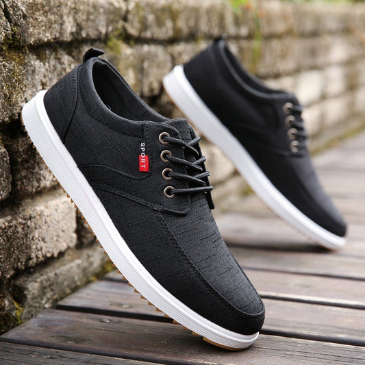 Black casual shoes with white soles on a wooden surface and stone wall background