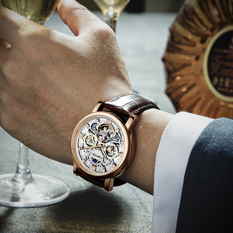 Close-up of a hand wearing a luxurious watch with a glass of wine in the background