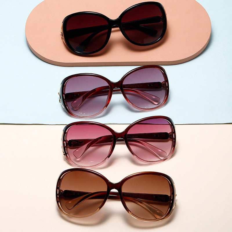 Four pairs of sunglasses with different colored lenses on a light blue and beige background.