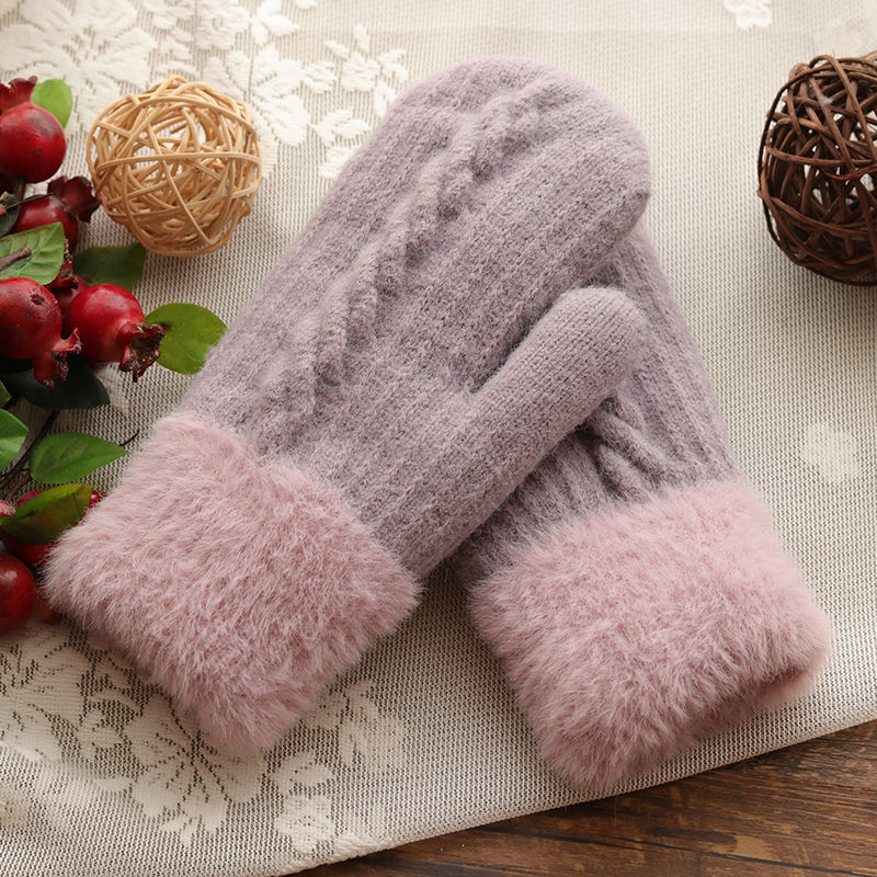 Pair of gray and pink fuzzy gloves on a decorative surface with pomegranates and spherical decorations.