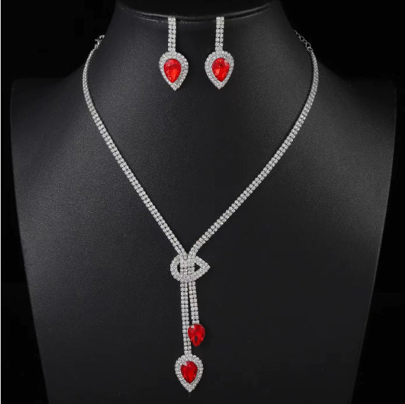Jewelry set with necklace and earrings featuring red heart-shaped stones on a black background